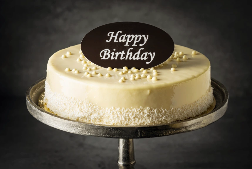 Raffaello Happy Birthday Cake - A smooth white chocolate and coconut cake, elegantly finished with a customisable "Happy Birthday" topper.